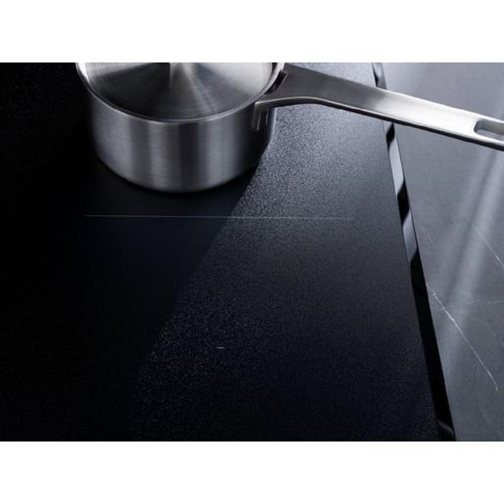 Ein glänzender Edelstahltopf steht auf der matten Kochzone des AEG Induktionskochfeldes.