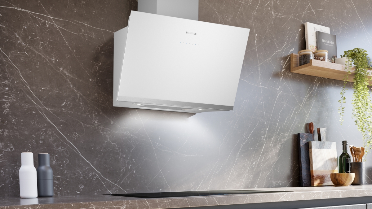 Lifestyle-Bild der an einer dunklen Marmorwand montierten weißen Haube, die das Kochfeld hell beleuchtet.