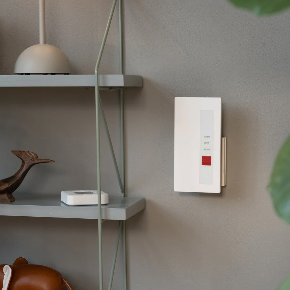 Das AVM FRITZ! Zigbee-Gateway an einer hellgrauen Wand montiert, zeigt die Integration in ein modernes Smart Home Ambiente.