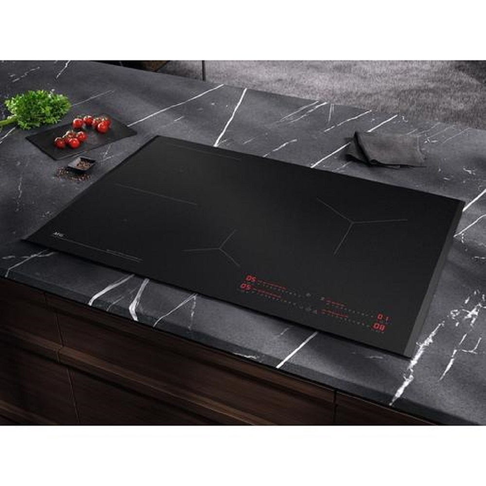 Ein flach eingebautes AEG Kochfeld in einer dunklen Marmor-Arbeitsplatte in einer modernen Küche.