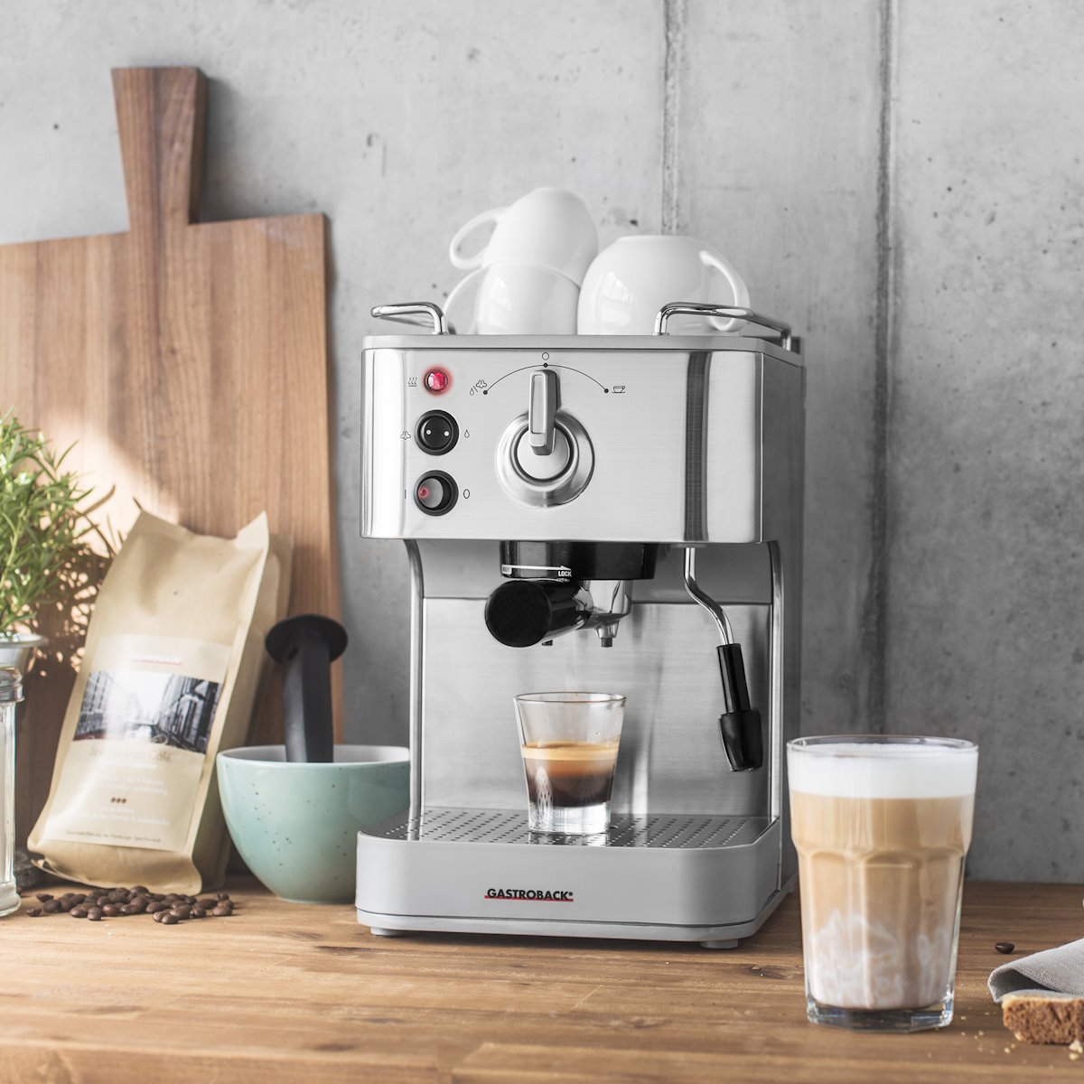 Gastroback Design Espresso Plus Espressomaschine auf einer Küchenarbeitsfläche aus Holz, mit Espresso und Latte Macchiato.