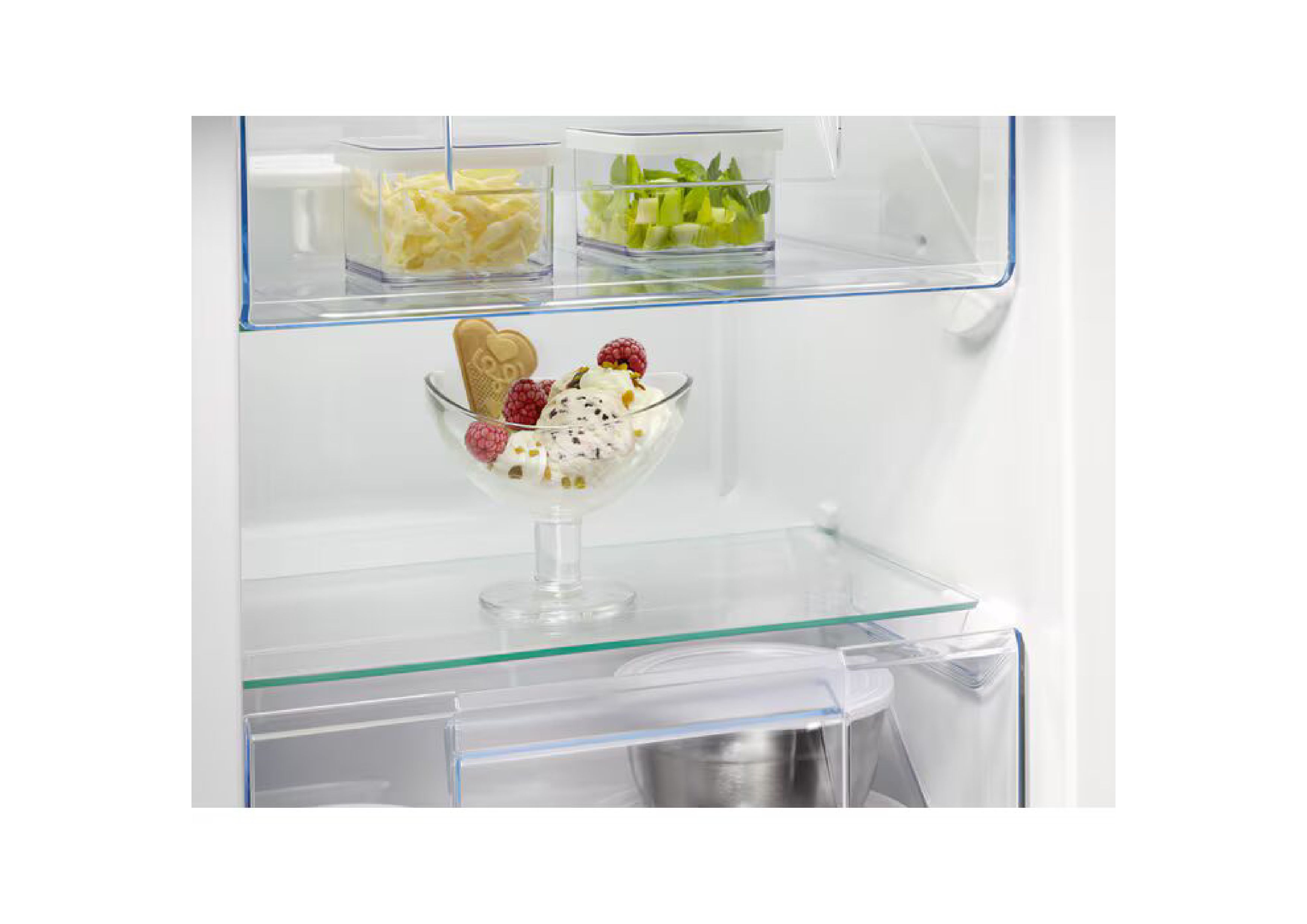 Nahaufnahme einer Gefrierschrankschublade mit einer dekorativen Glasschale voller Eiscreme, Beeren und einem Keks