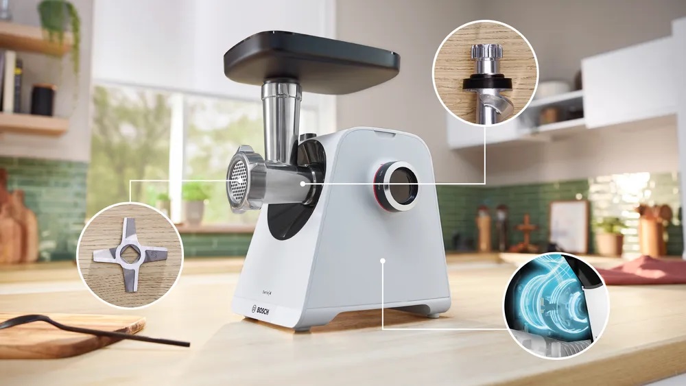 Bosch MFWS420W Kompakt-Fleischwolf in einer modernen Küche, mit Kreisen, die wichtige Merkmale hervorheben: das Klingendesign, den Motor und den Befestigungsmechanismus des Kopfes.