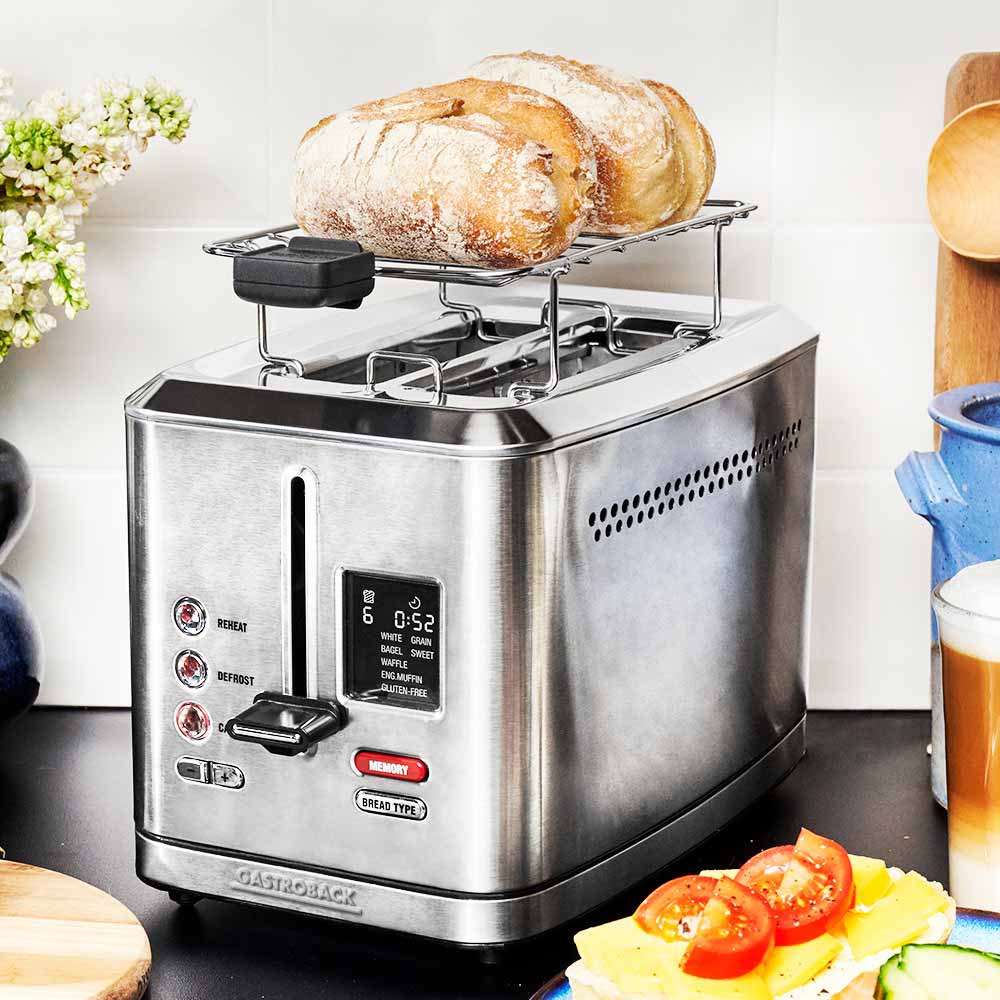 Der Gastroback Toaster mit Brötchenaufsatz, auf dem zwei helle Brötchen erwärmt werden, in einer Küche mit Frühstücksanrichtung.