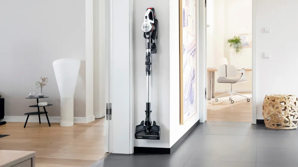 BOSCH BSS711W Stielstaubsauger platzsparend hängend an der Wandhalterung aufbewahrt.