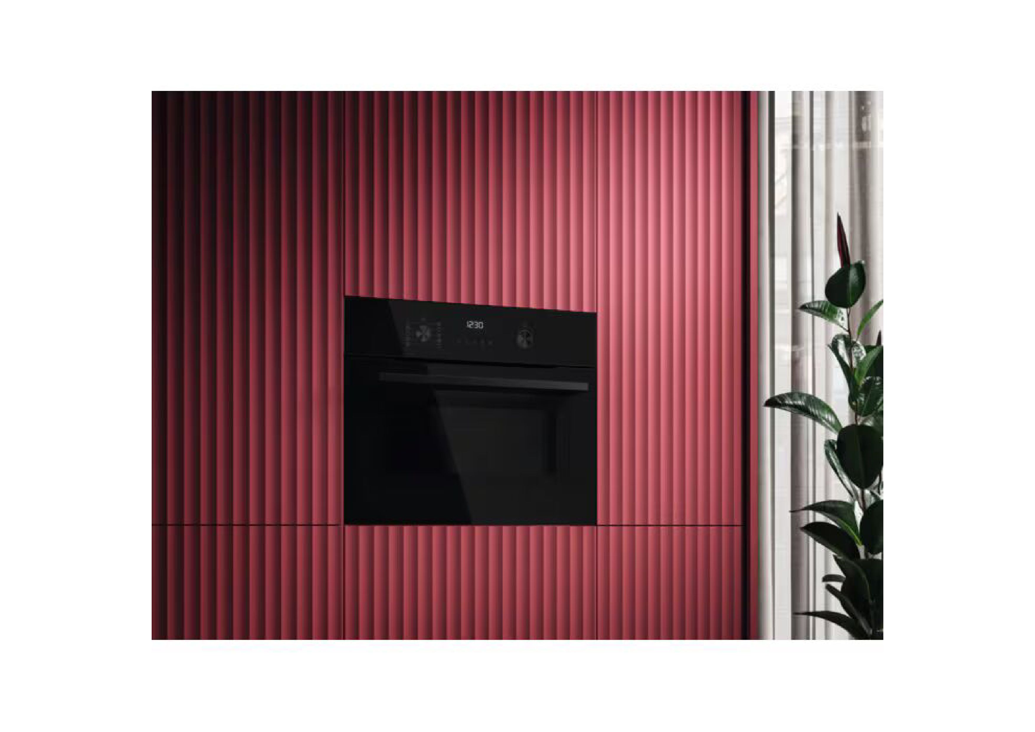 Built-in compact oven in a modern red kitchen next to a houseplant.