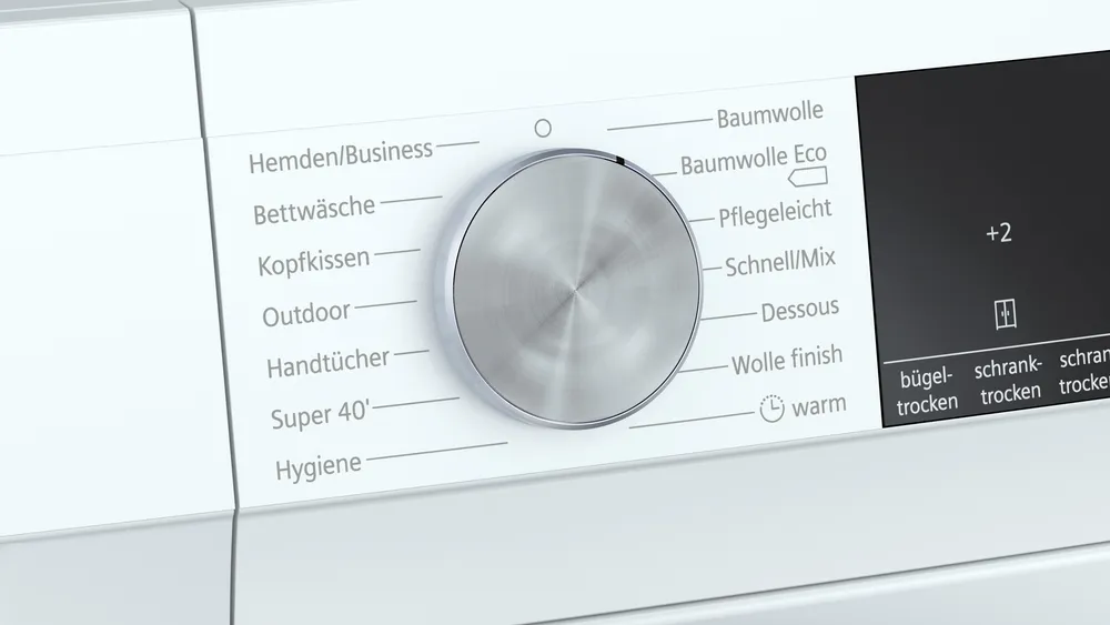 Detailansicht Programmwahlknopf und iSensoric Nahaufnahme des silbernen Programmwahlknopfs des Trockners, der Programme wie Baumwolle Eco, Outdoor und Hygiene zeigt.