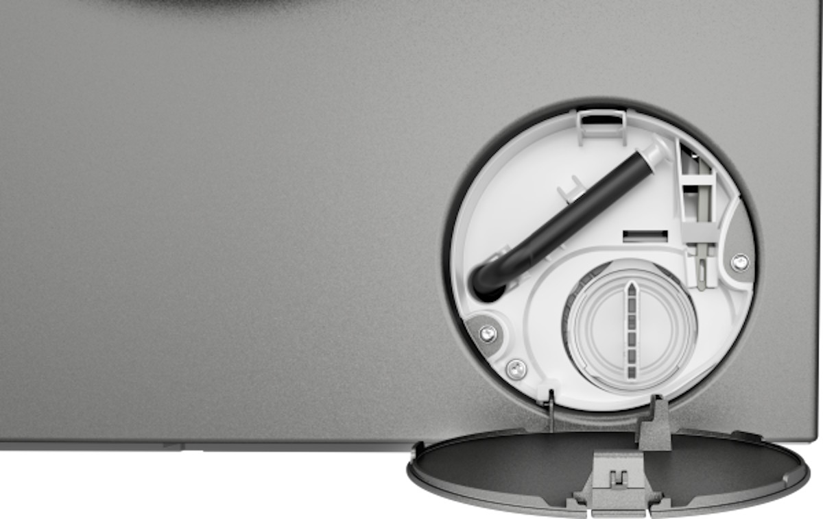 Geöffnete Serviceklappe an der Front unten rechts mit Fremdkörperfalle und Schlauch für den Laugen-Not-Ablauf.