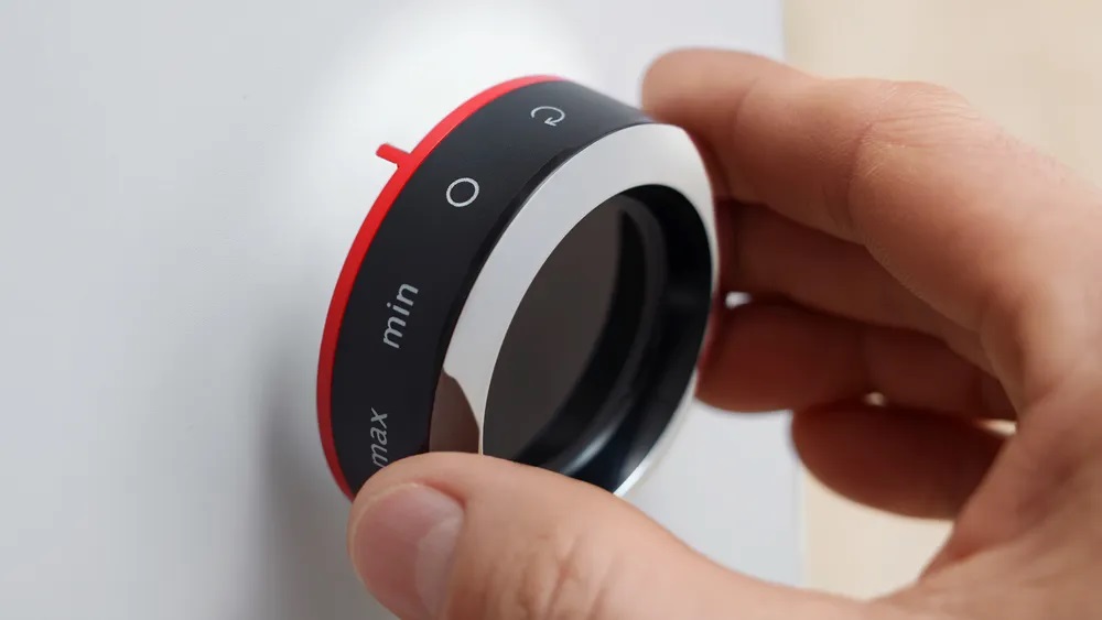 Bosch MFWS420W Kompakt-Fleischwolf – Drehregler Bedienung Nahaufnahme einer Hand, die den Drehregler des Bosch MFWS420W Kompakt-Fleischwolfs betätigt, mit "min" und "max" Einstellungen.