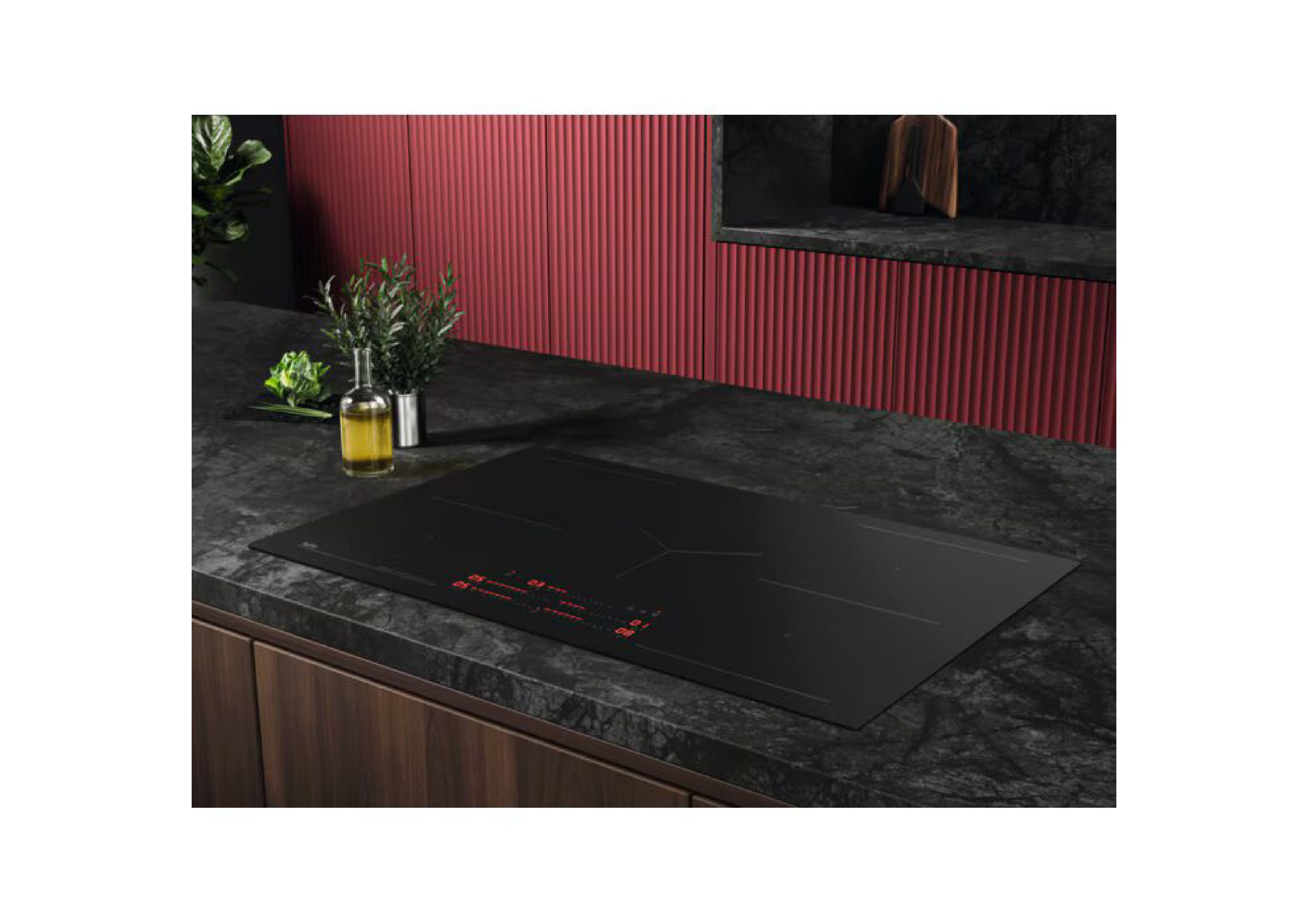 Wide-angle shot of the AEG induction hob in a modern kitchen with a red back wall, olive oil, and herbs.