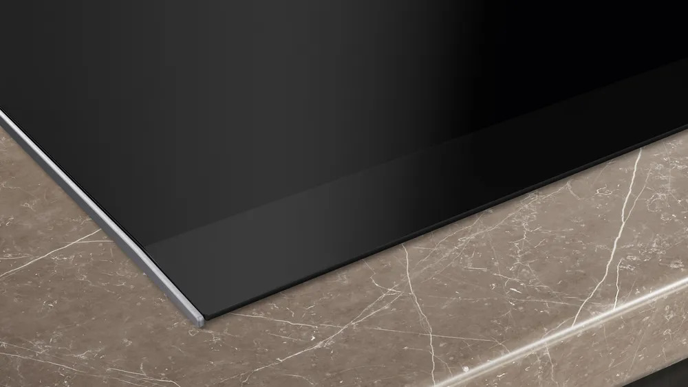Nahaufnahme der schlanken Edelstahlkante und des flachen Designs des Siemens EX675HEC1E Induktionskochfelds. Siemens iQ700 EX675HEC1E Induktionskochfeld – Elegantes Design
