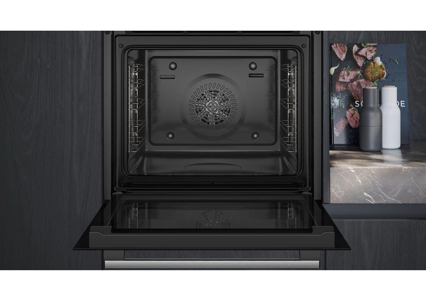 Blick in den geöffneten, leeren Garraum eines schwarzen Einbaubackofens mit sichtbarem Rückwandventilator und Einhängegittern.