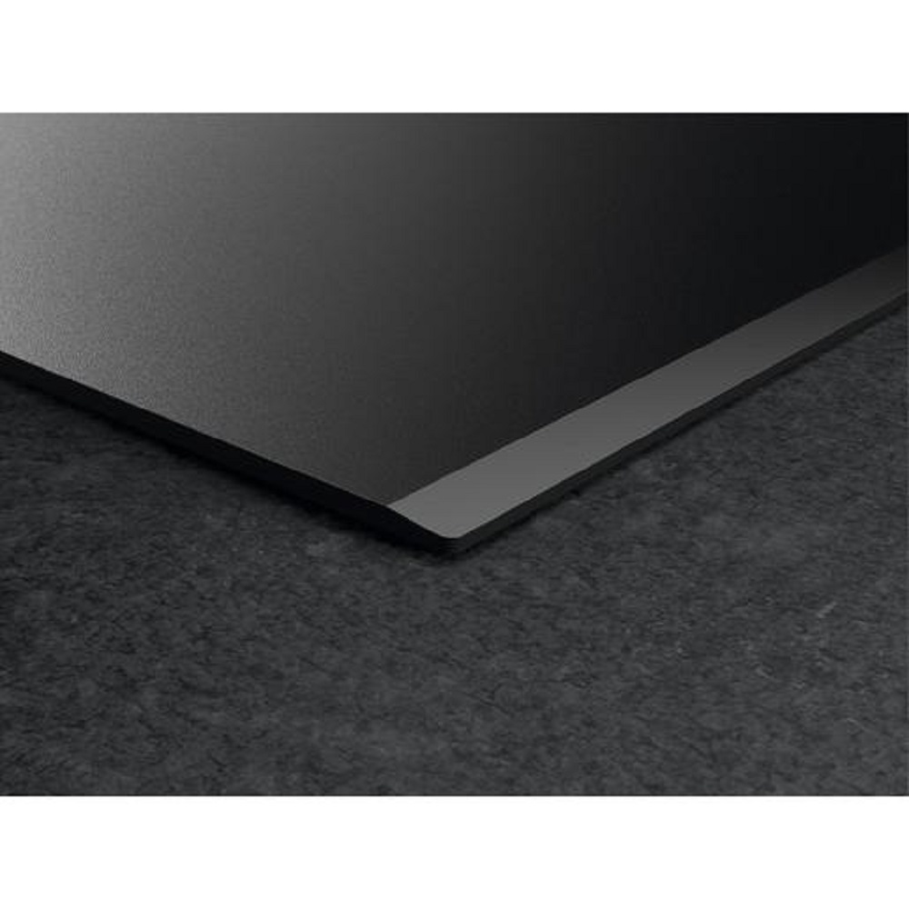 Detailaufnahme der flachen Kante des Kochfeldes auf einer dunklen, strukturierten Arbeitsplatte.