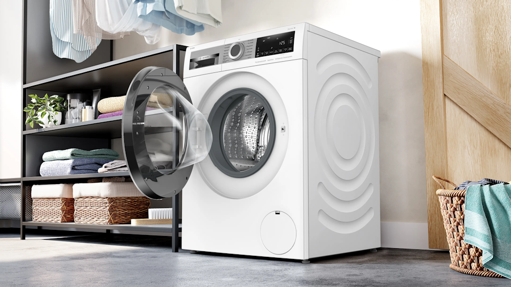 Bosch WGG244F40 Waschmaschine mit geöffneter Tür in stilvollem Waschraum mit Wäschekorb und Regal