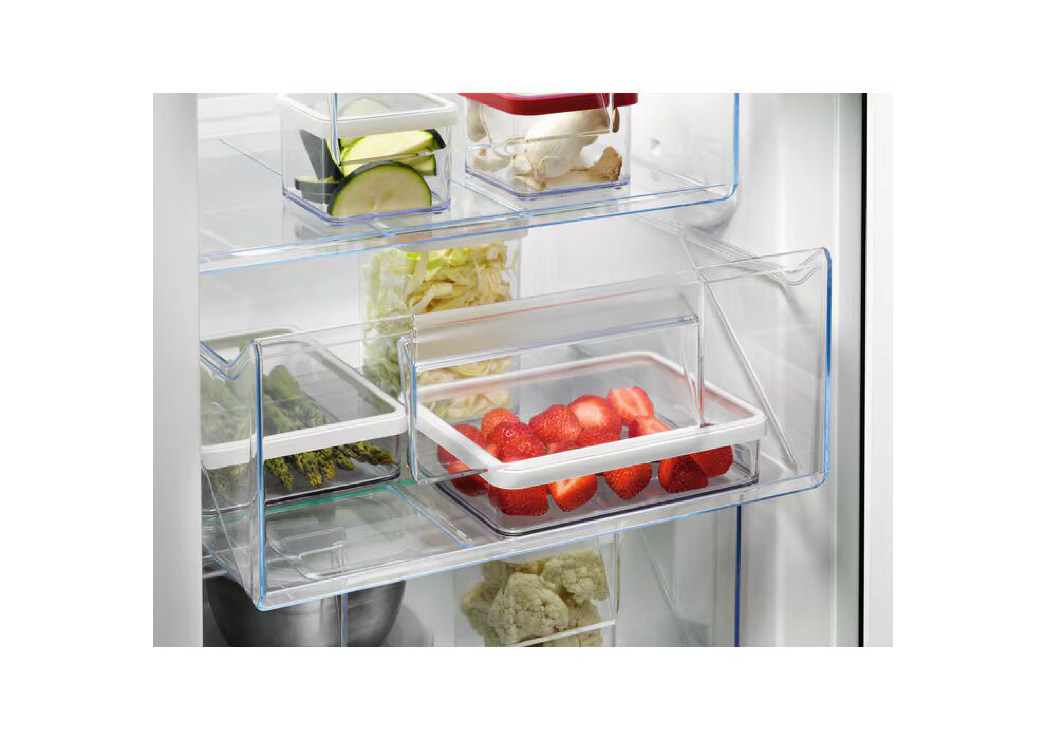 Nahaufnahme von zwei geöffneten transparenten Gefrierschrankschubladen, gefüllt mit Zucchini, Pilzen, Spargel und Erdbeeren