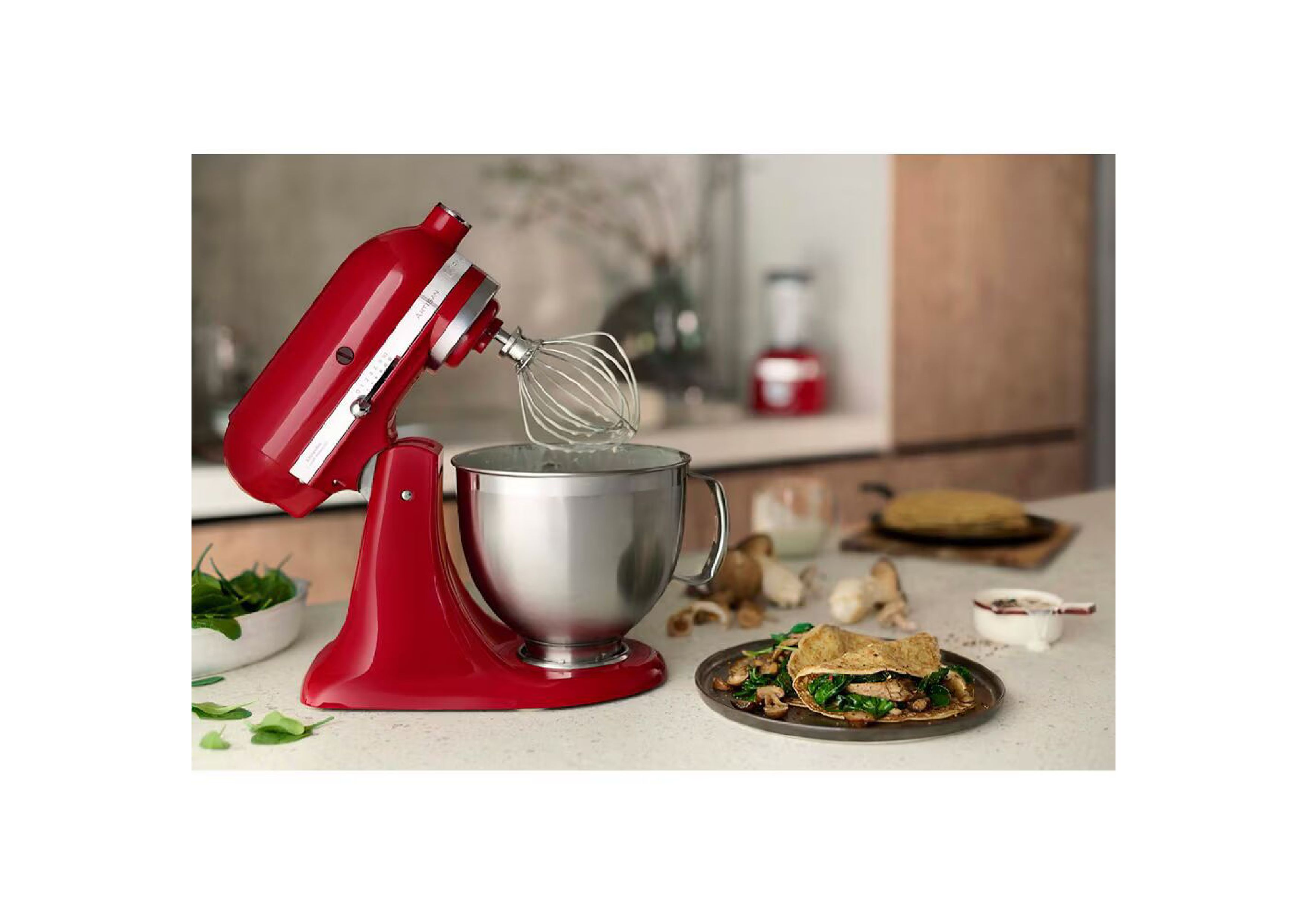 KitchenAid Artisan with tilted head and whisk attachment preparing savory crepes in a kitchen setting.