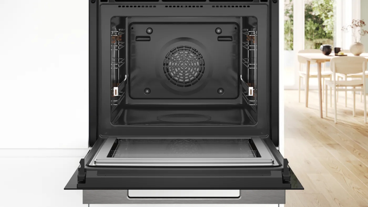 Bosch HMG776NB1 mit geöffneter Ofentür, Blick in den 67-Liter-Garraum mit emailliertem Backblech, Kombirost und Universalpfanne