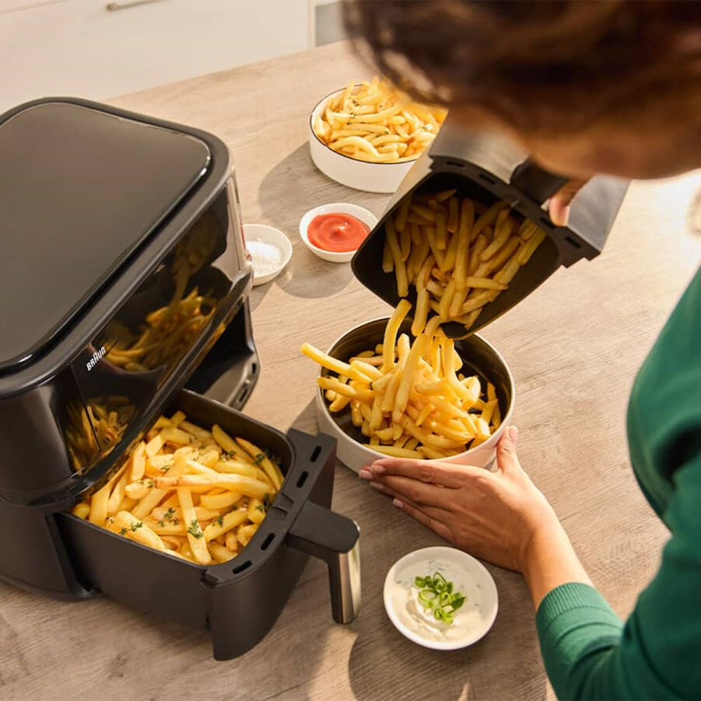 Heißluftfritteuse im Betrieb: Linke Kammer mit Pommes Frites, rechte Kammer mit Hähnchenschenkeln.