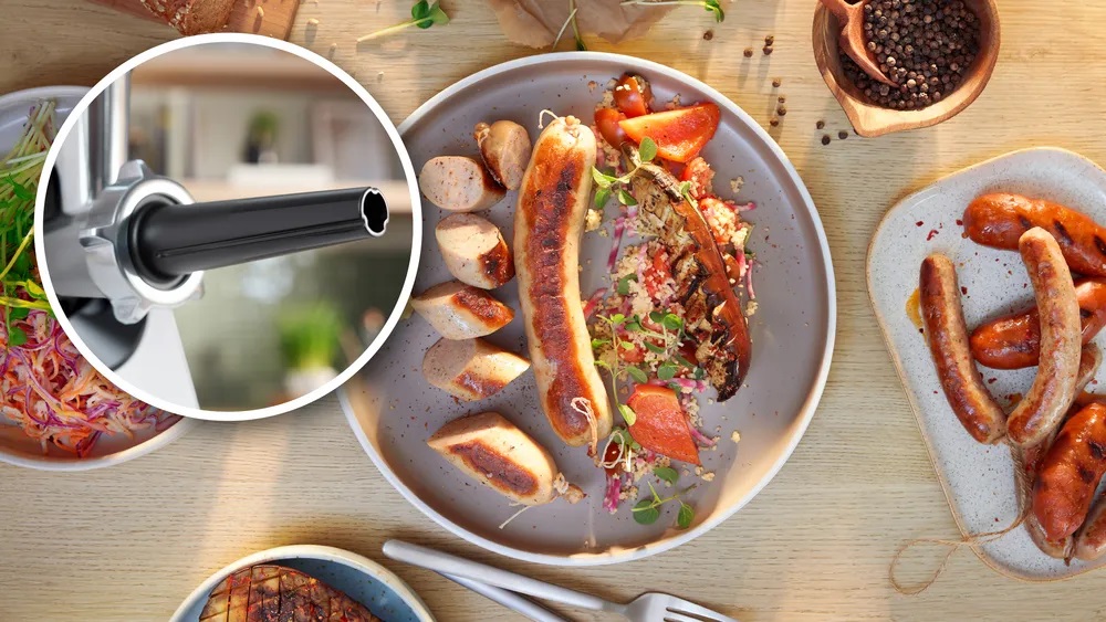 Bosch MFWS420W Kompakt-Fleischwolf – Wurstfüller-Aufsatz Ein Teller mit gegrillten Würsten und Beilagen, daneben ein runder Ausschnitt, der den Wurstfüller-Aufsatz des Bosch MFWS420W Kompakt-Fleischwolfs zeigt.