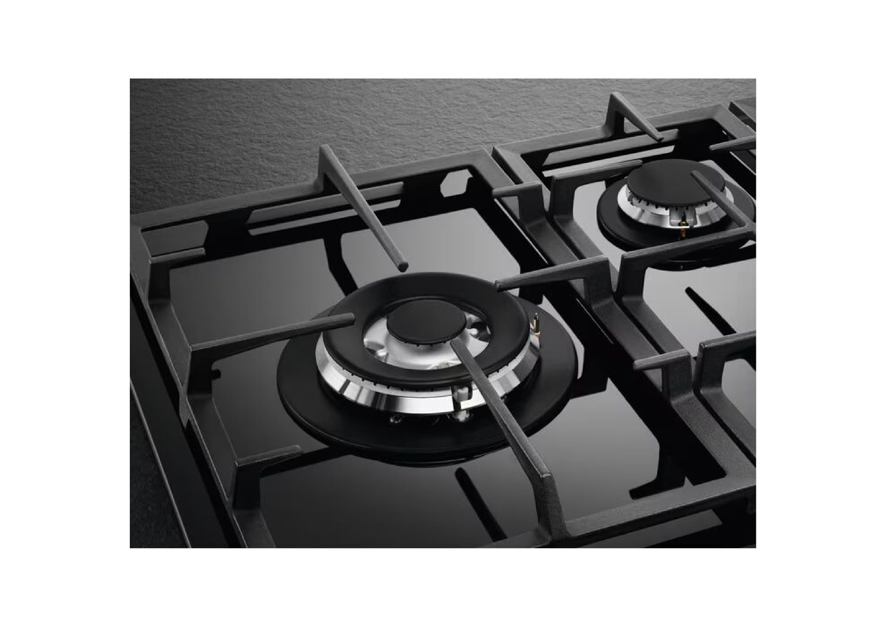 Close-up of cast iron pan supports and gas burners on a black glass surface